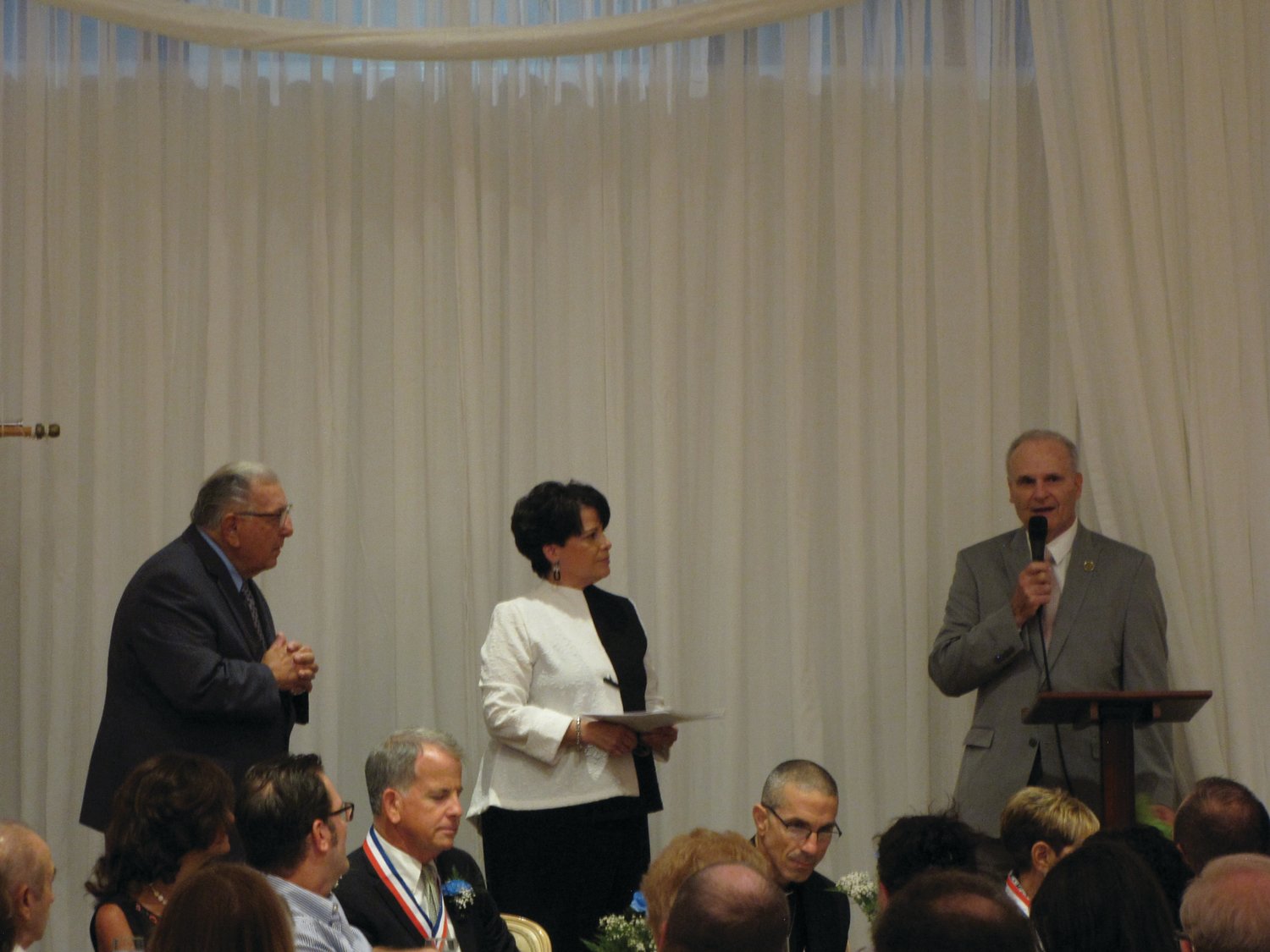 PAST PRESIDENT: Fred Vincent, right, who served as president of the Cranston Hall of Fame’s Board of Directors for a decade, was recognized for his service during last week’s installation dinner. He is joined on stage by board vice president Michael Traficante and Cindy Soccio, the board’s new president.